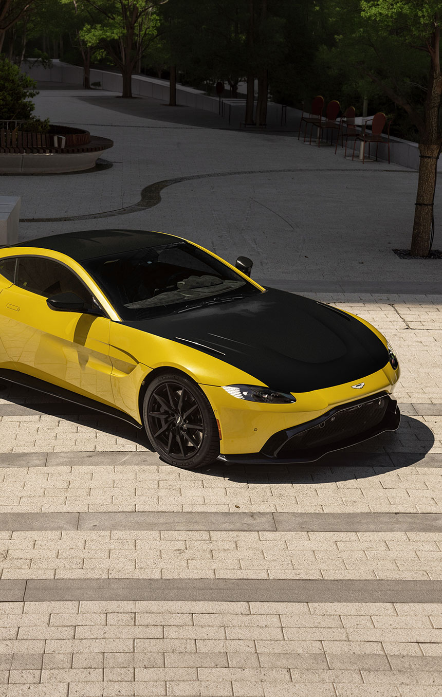 Yellow sports car with a contrasting black hood parked on a paved street, highlighting its sleek exterior and the enhanced finish achievable with LLumar Select Black paint protection film. 