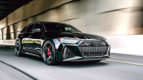 A black high‑performance wagon driving at speed through a tunnel, with blurred pavement and walls creating a sense of motion.