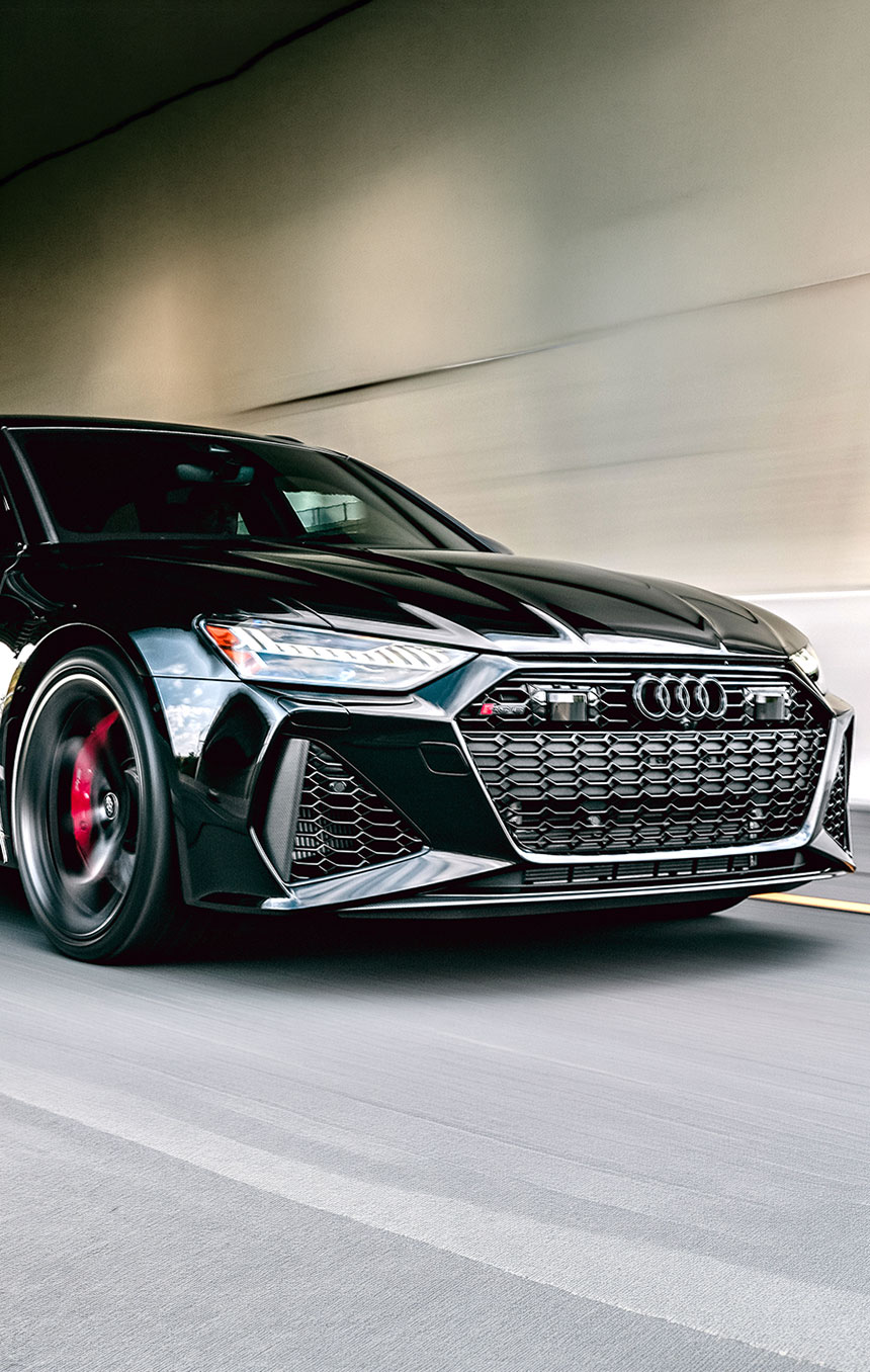 Black performance car driving at speed through a tunnel, highlighting its glossy finish and ideal conditions for showcasing automotive paint protection film. 