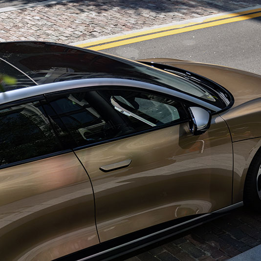 Gold and black luxury sedan parked on a brick street with tinted windows and modern design details.