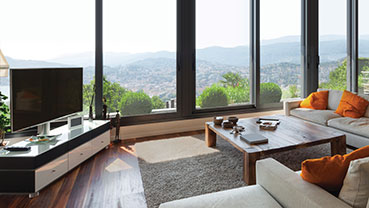 Living room with large windows overlooking hills and a wood coffee table.
