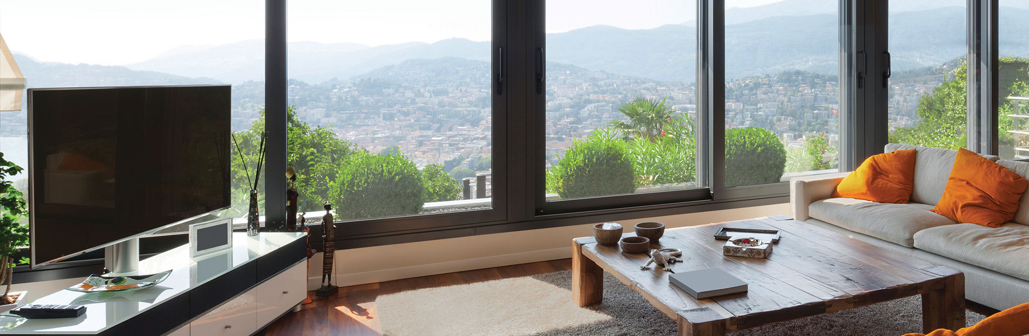 Living room with large windows overlooking hills and a wood coffee table. 