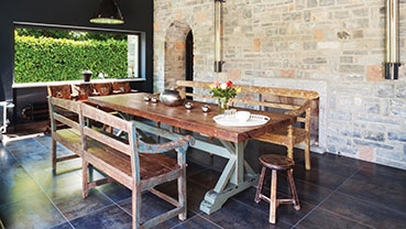 Rustic dining area with stone walls and a wooden table.