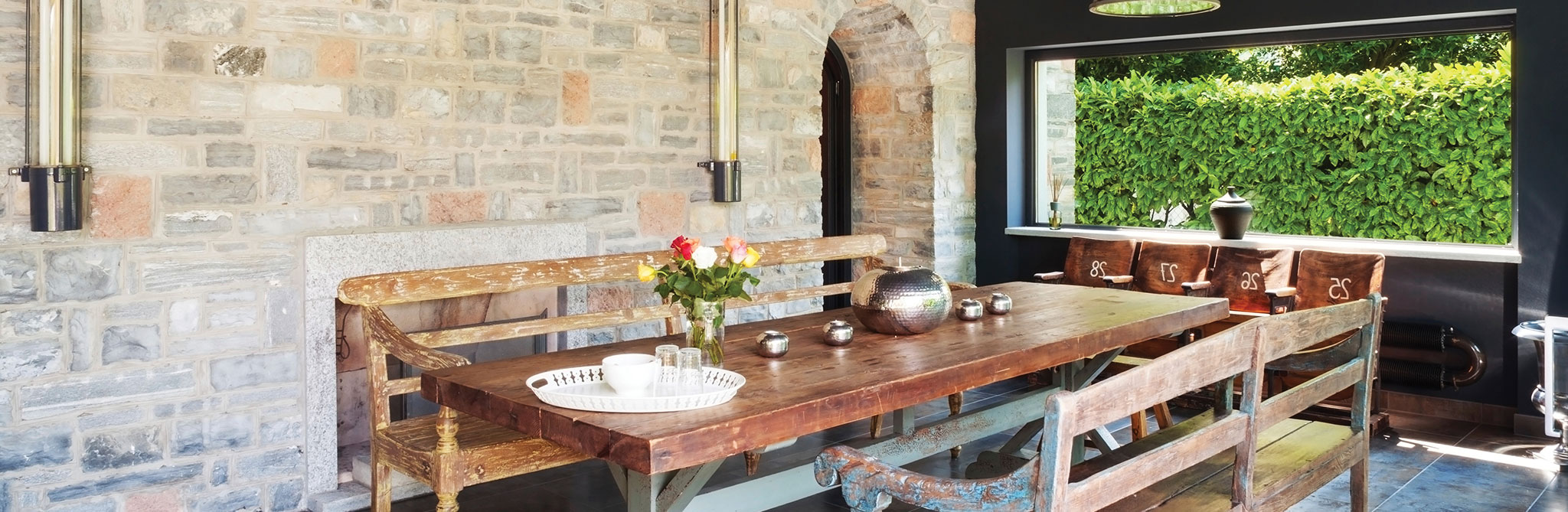 Rustic dining area with stone walls and a wooden table. 