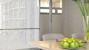 Light-colored meeting area with a bowl of green apples on the table, next to a glass partition featuring a white leaf-patterned privacy film.