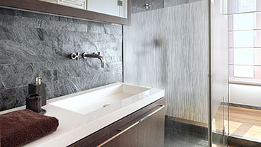 Modern bathroom with a stone accent wall and frosted glass shower.