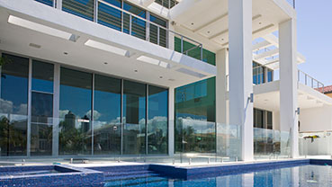 Modern home exterior with large glass doors opening to a pool.