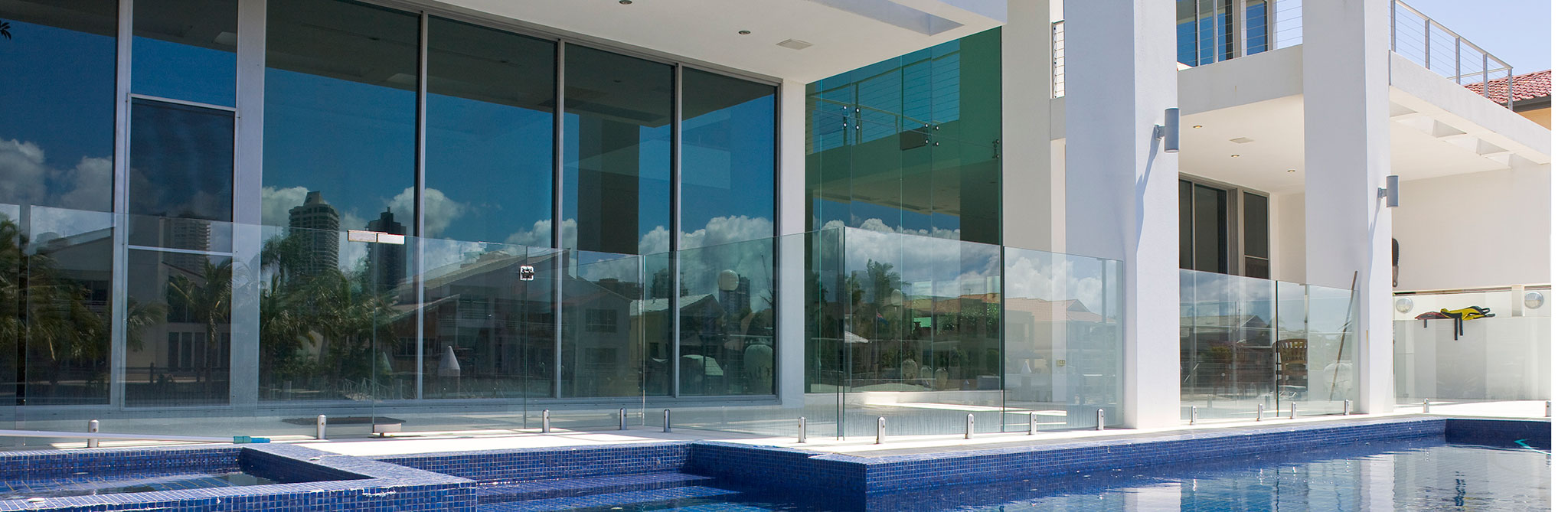 Modern home exterior with large glass doors opening to a pool. 