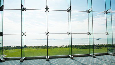 Large glass windows overlooking a landscaped lawn and ocean view.