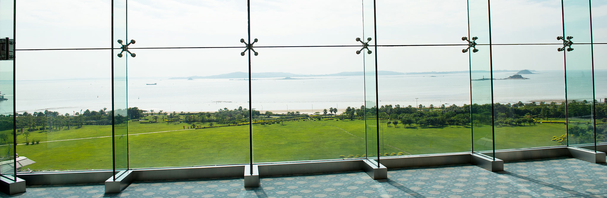 Large glass windows overlooking a landscaped lawn and ocean view. 