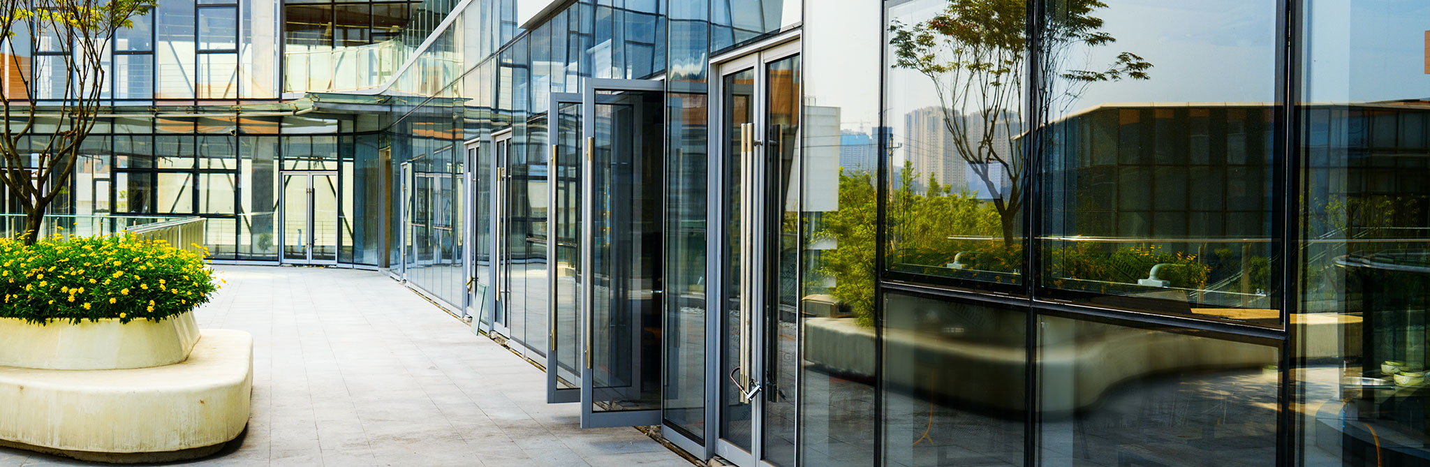 Modern commercial building with reflective glass walls and open exterior walkway. 