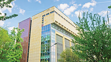 Modern building exterior with large windows surrounded by trees.