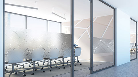 Office meeting room with glass walls covered in geometric frosted film patterns, with chairs and tables visible behind the semi‑opaque design.