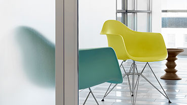 Bright room with colorful chairs behind a frosted glass divider.