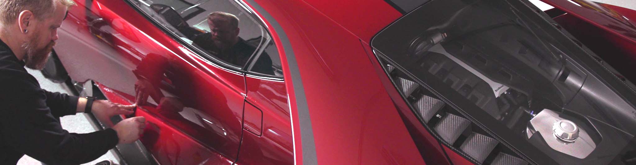 Paint Protection Film installer applying film to the door of a red sports car 
