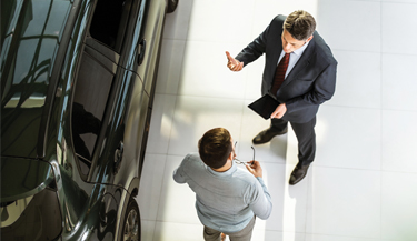 Autohändler im Gespräch mit einem Kunden über die Vorteile von Fensterfolien 